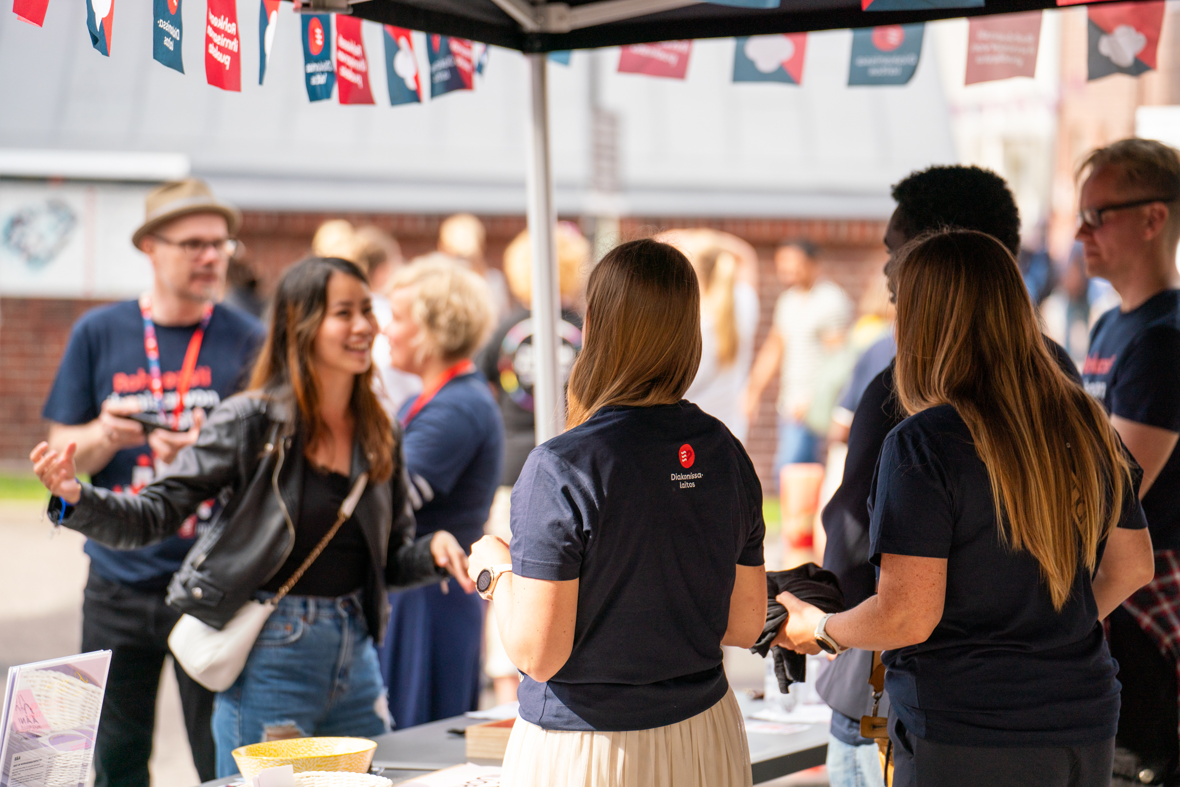 Ihmisiä keskustelemassa ja jakamassa tietoa Diakonissalaitoksen tapahtumapisteellä.