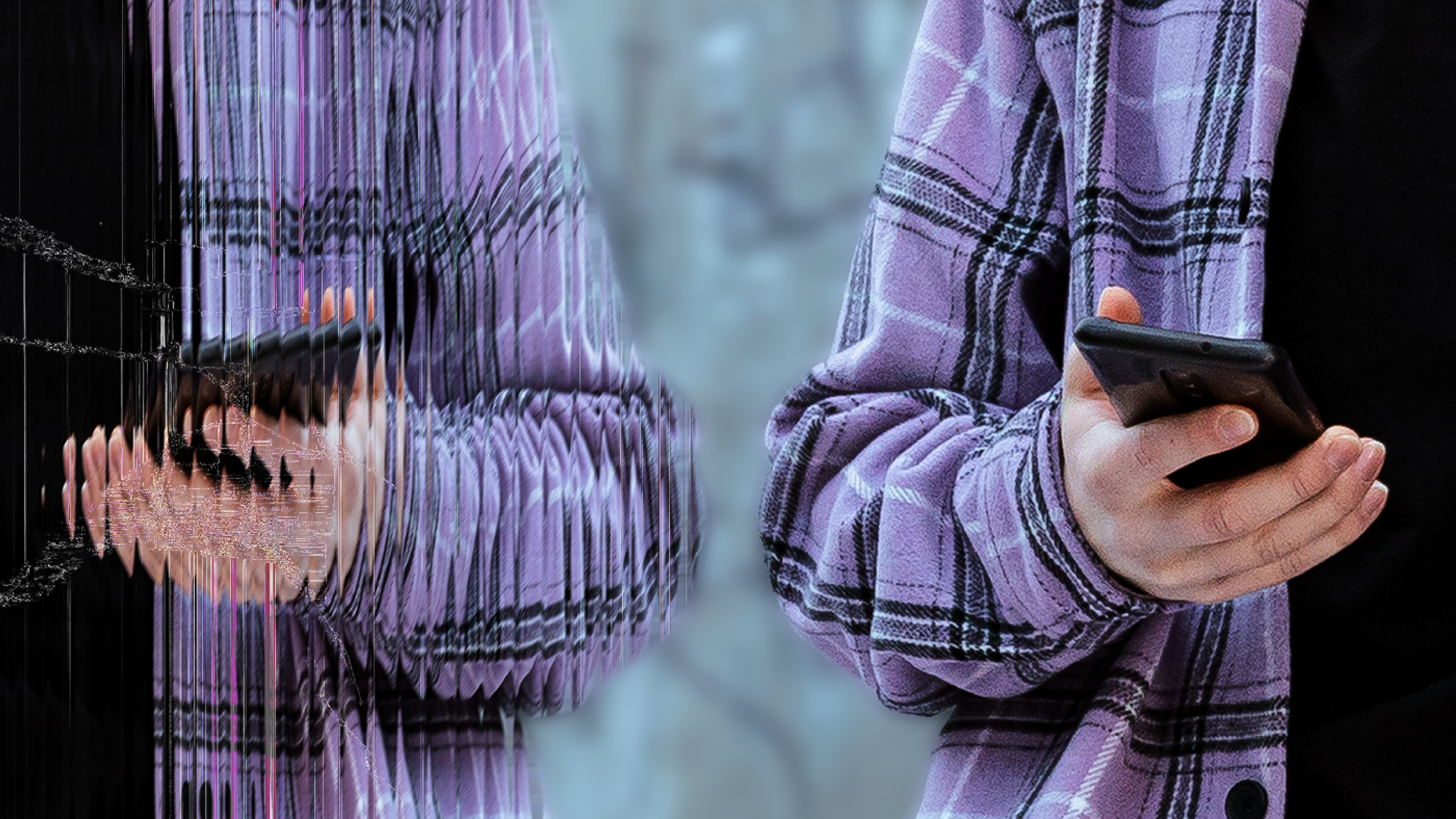 Henkilö kädessään älypuhelin, hänellä päällä violetti ruudullinen takki.