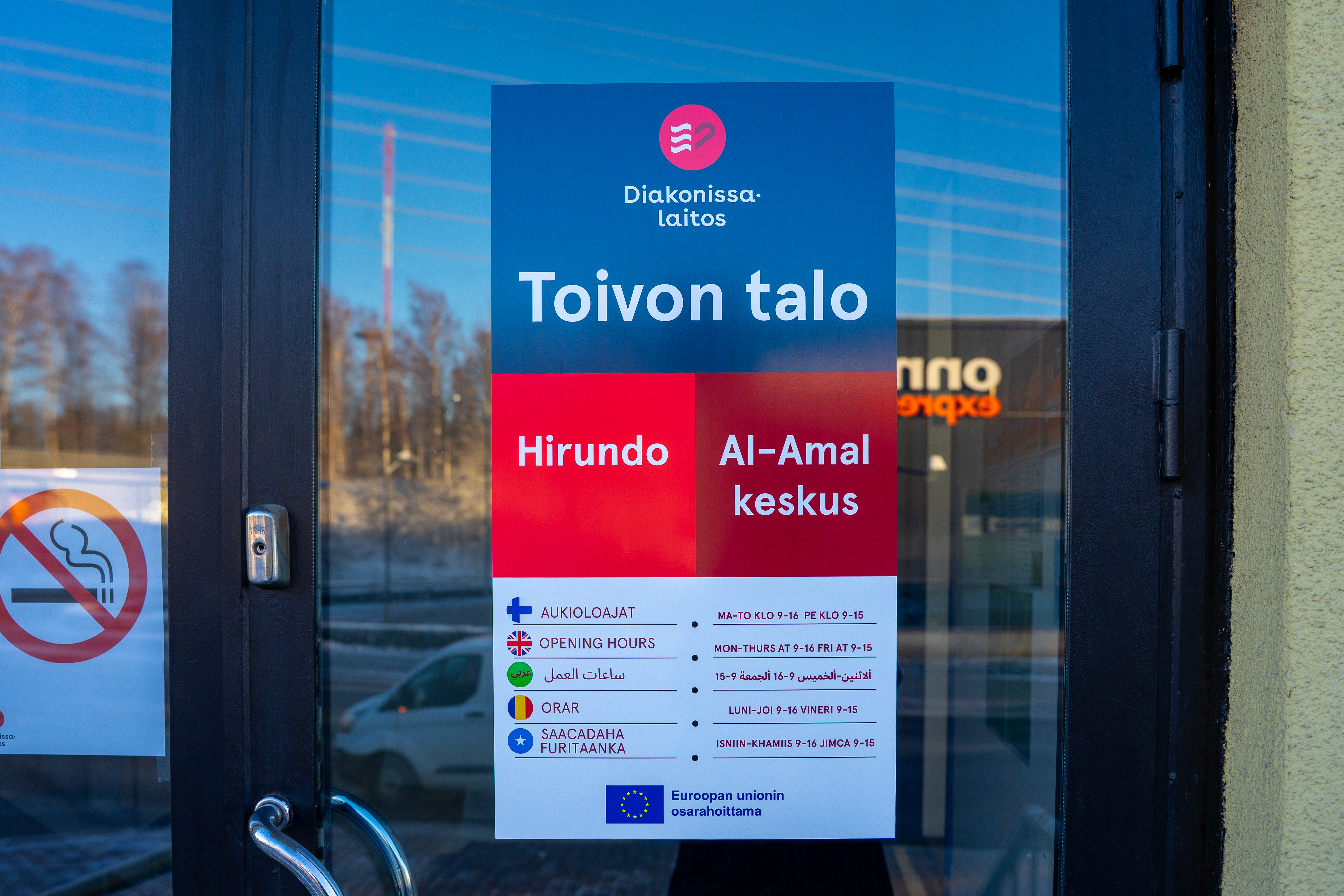 Oven lasissa oleva kyltti, jossa lukee Diakonissalaitos Toivon talo, Hirundo ja Al-Amal keskus sekä aukioloajat ja palvelut.