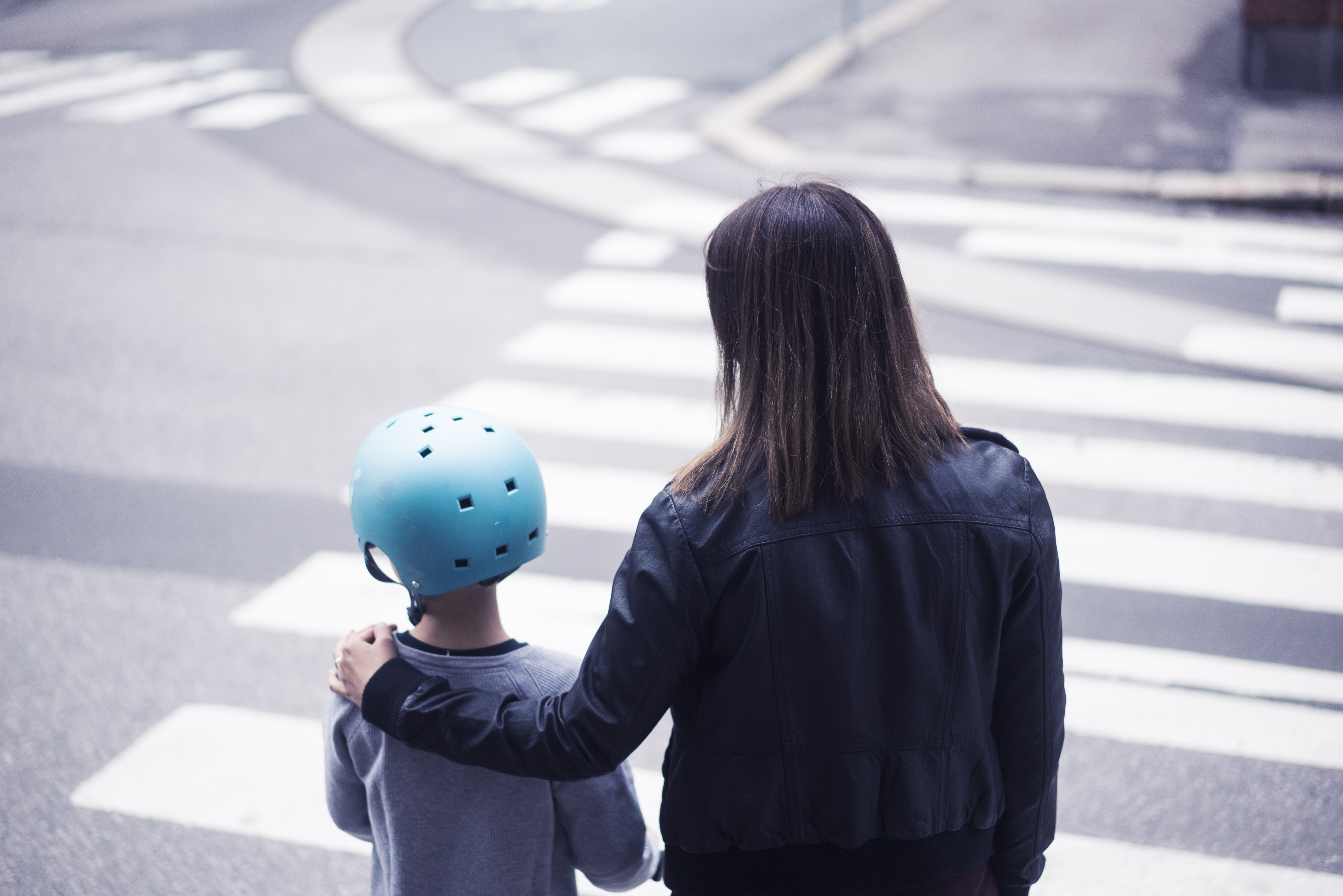 Aikuinen ja lapsi seisovat rinnakkain suojatien reunalla.