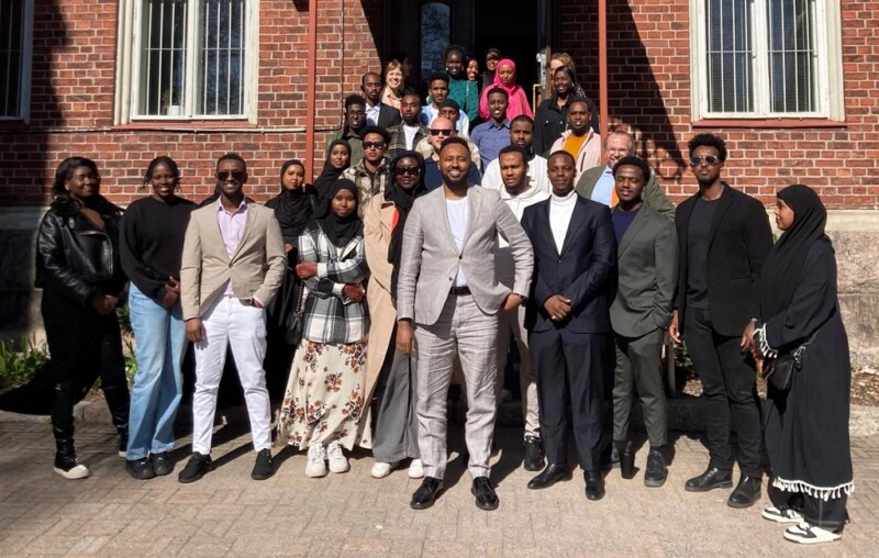 Ryhmä nuoria rauhanverkoston jäseniä seisoo rakennuksen edessä ryhmäkuvassa.