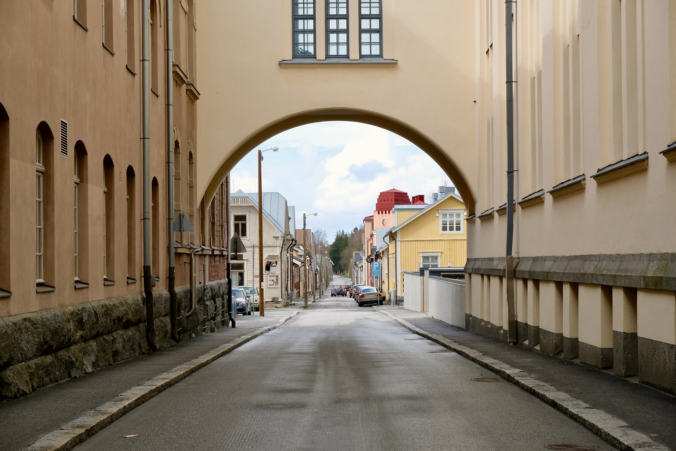 Kapea katu, jonka päällä on kaari, ja kadun varrella vanhoja rakennuksia sekä autoja.