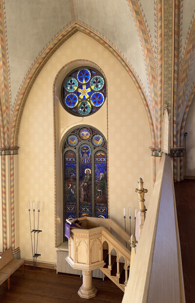 Kirkkotila, jossa lasimaalaus saarnatuolin takana.