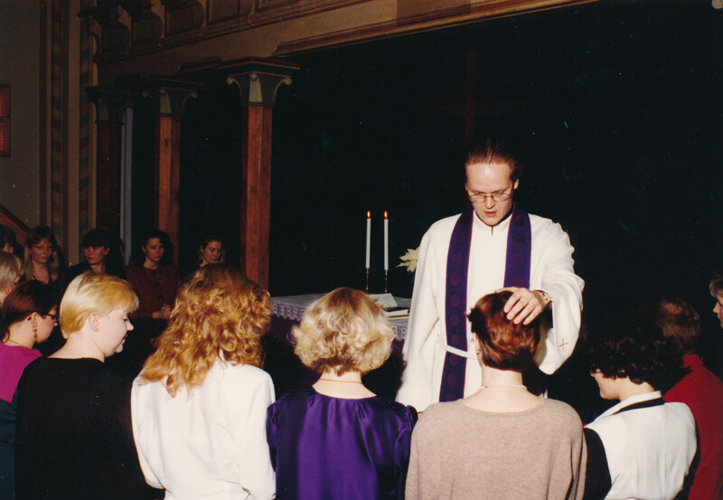 Pappi siunaa ryhmää ihmisiä kirkon alttarilla 1990-luvulla.