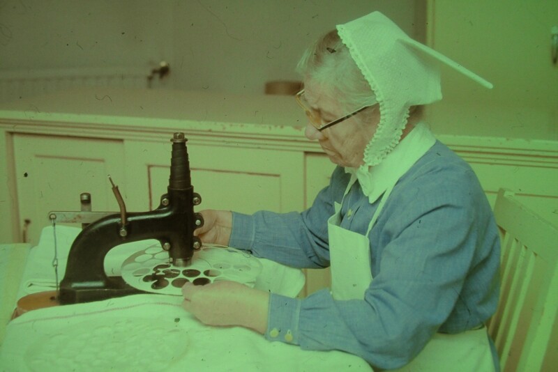 Nainen leikkaa ehtoollisleipiä leikkurilla.