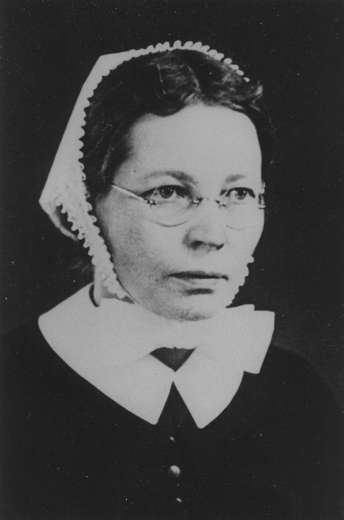 Mustavalkoinen kuva naisesta, jolla on silmälasit ja perinteinen diakonissan puku, mukaan lukien valkoinen kaulus ja rusettimyssy.