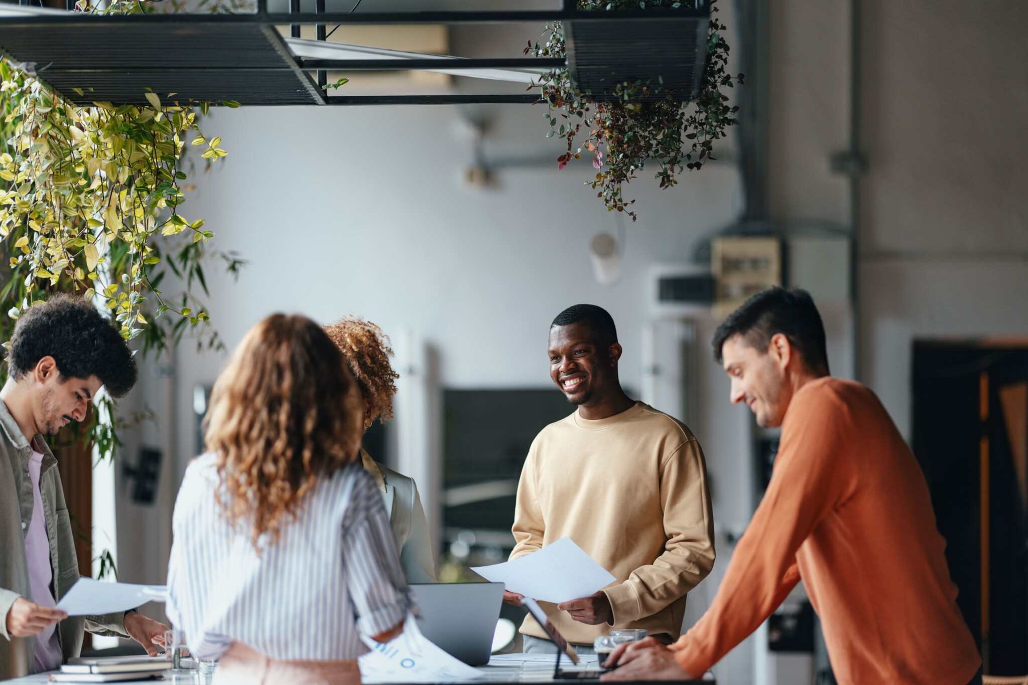 Monimuotoinen ryhmä aikuisia keskustelee ja työskentelee yhdessä modernissa toimistoympäristössä.