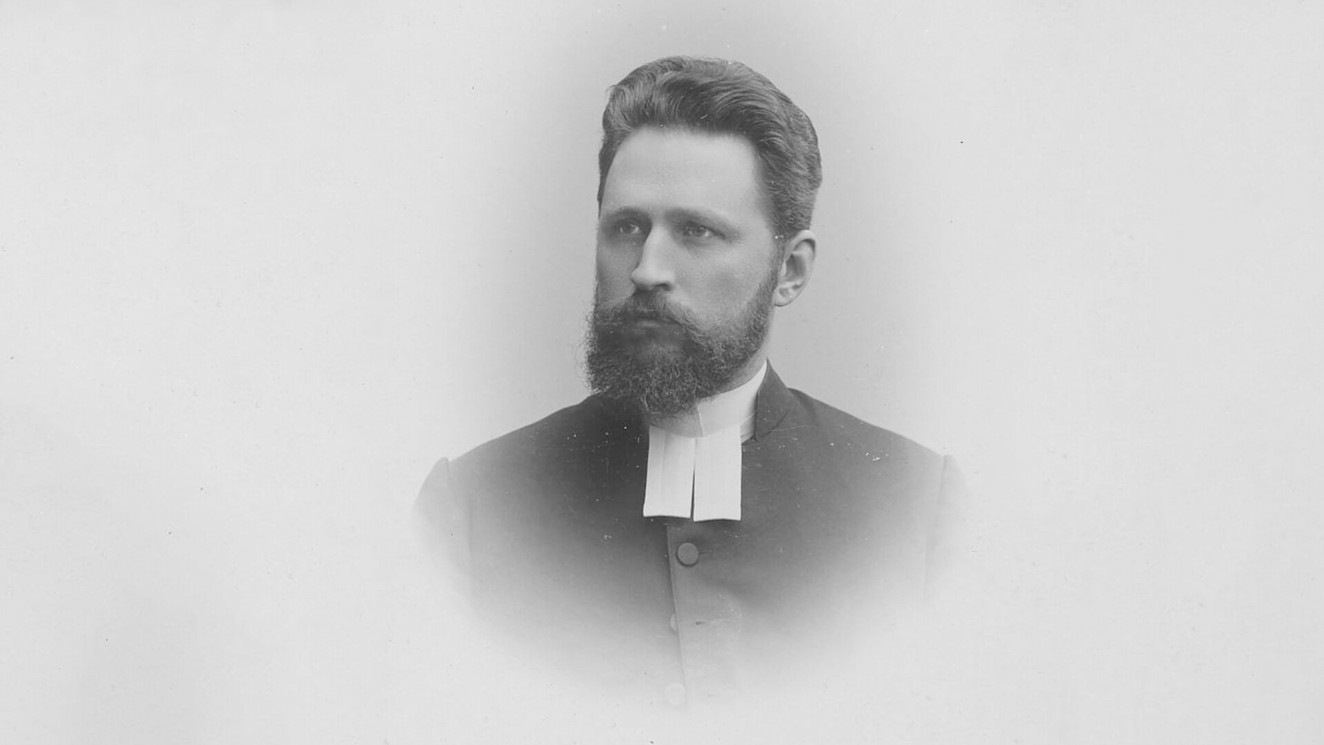 Mustavalkoinen kuva parrakkaasta miehestä.