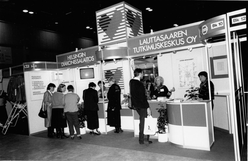 Messuosasto, jossa ihmiset keskustelevat ja tutustuvat esitteisiin Helsingin Diakonissalaitoksesta ja Lauttasaaren Tutkimuskeskus Oy:stä.