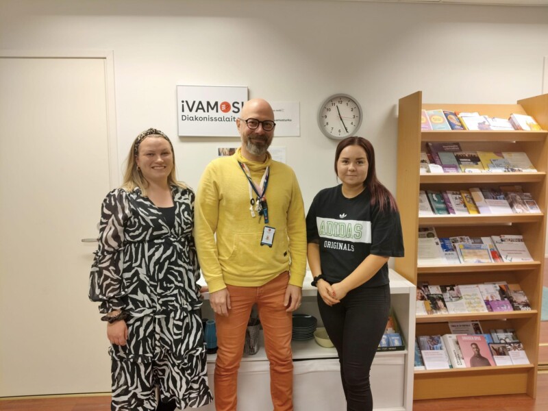 Kolme ihmistä seisoo rinnakkain ja katsoo hymyillen kameraan.