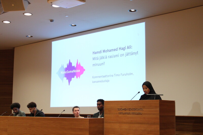 Nuori nainen pitää puhetta puhujakorokkeella.