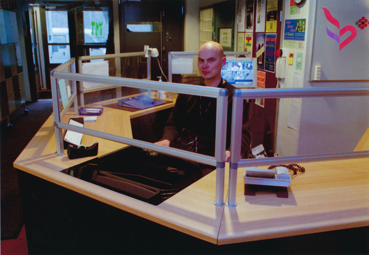 Mies istuu vastaanottotilassa lasiseinän takana.