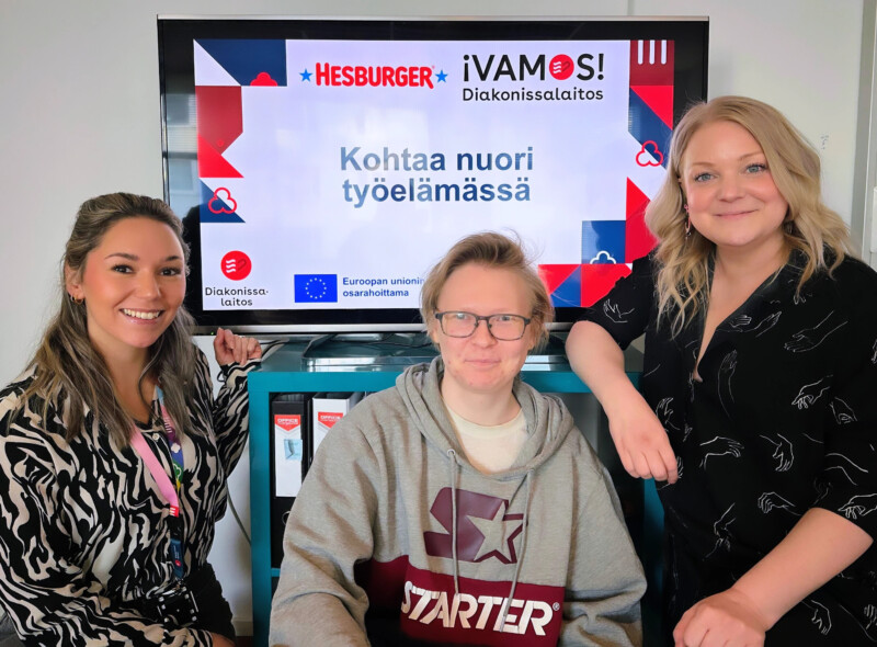 Kolme ihmistä katsoo hymyillen kameraan.