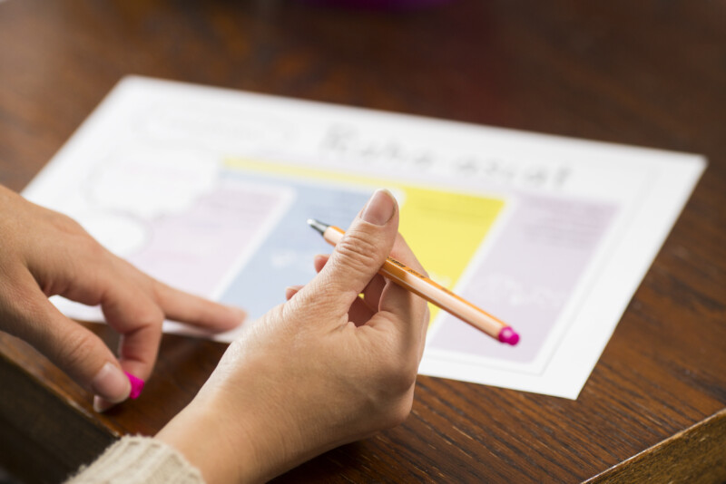 Käsi pitelee kynää.