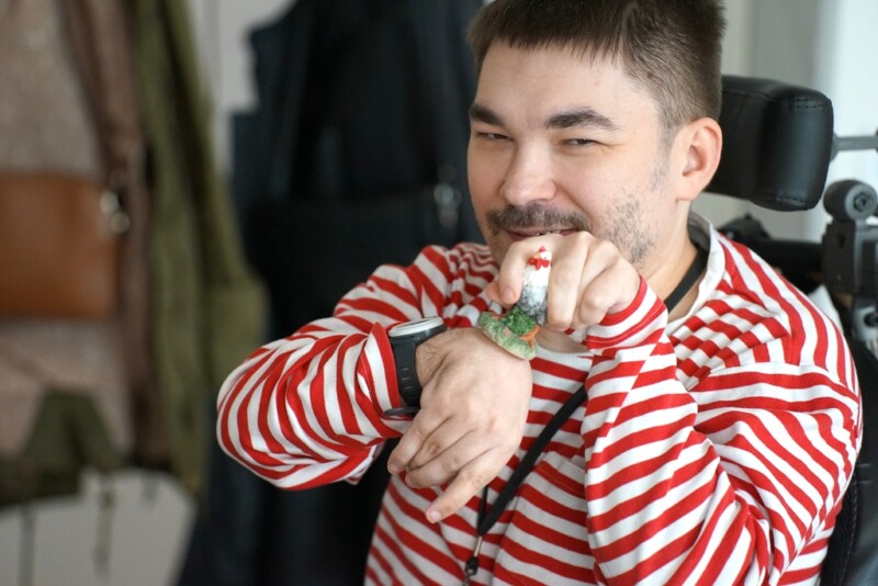 Punaraidalliseen paitaan pukeutuneella miehellä on kädessä pieni kanan pienoismalli.