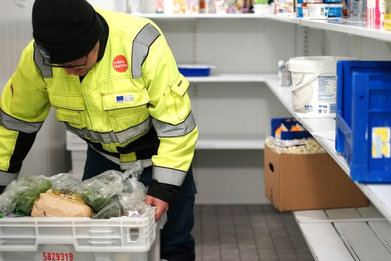 Keltatakkinen mies nostaa ruokalaatikkoa.