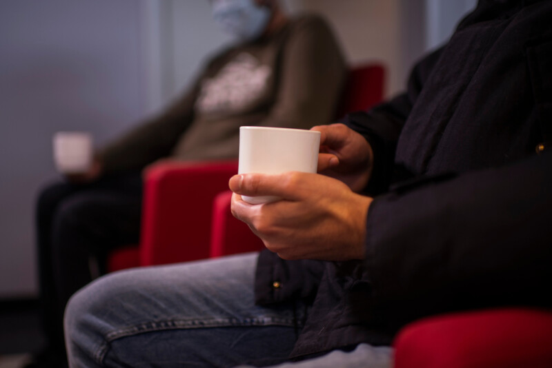 Ihminen istuu odotushuoneessa ja juo kahvia.