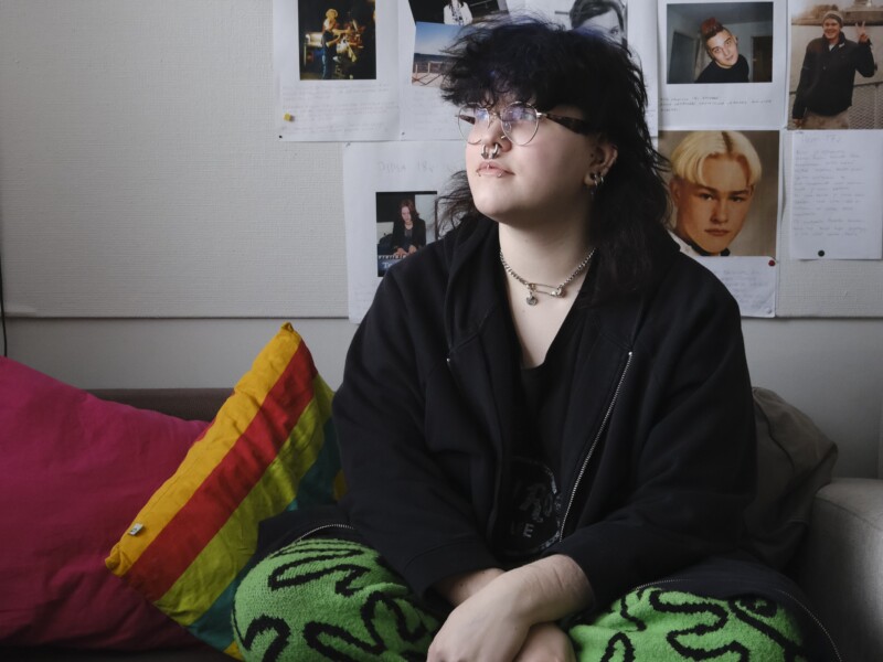 Nuori istuu sohvalla ja katsoo ylöspäin.