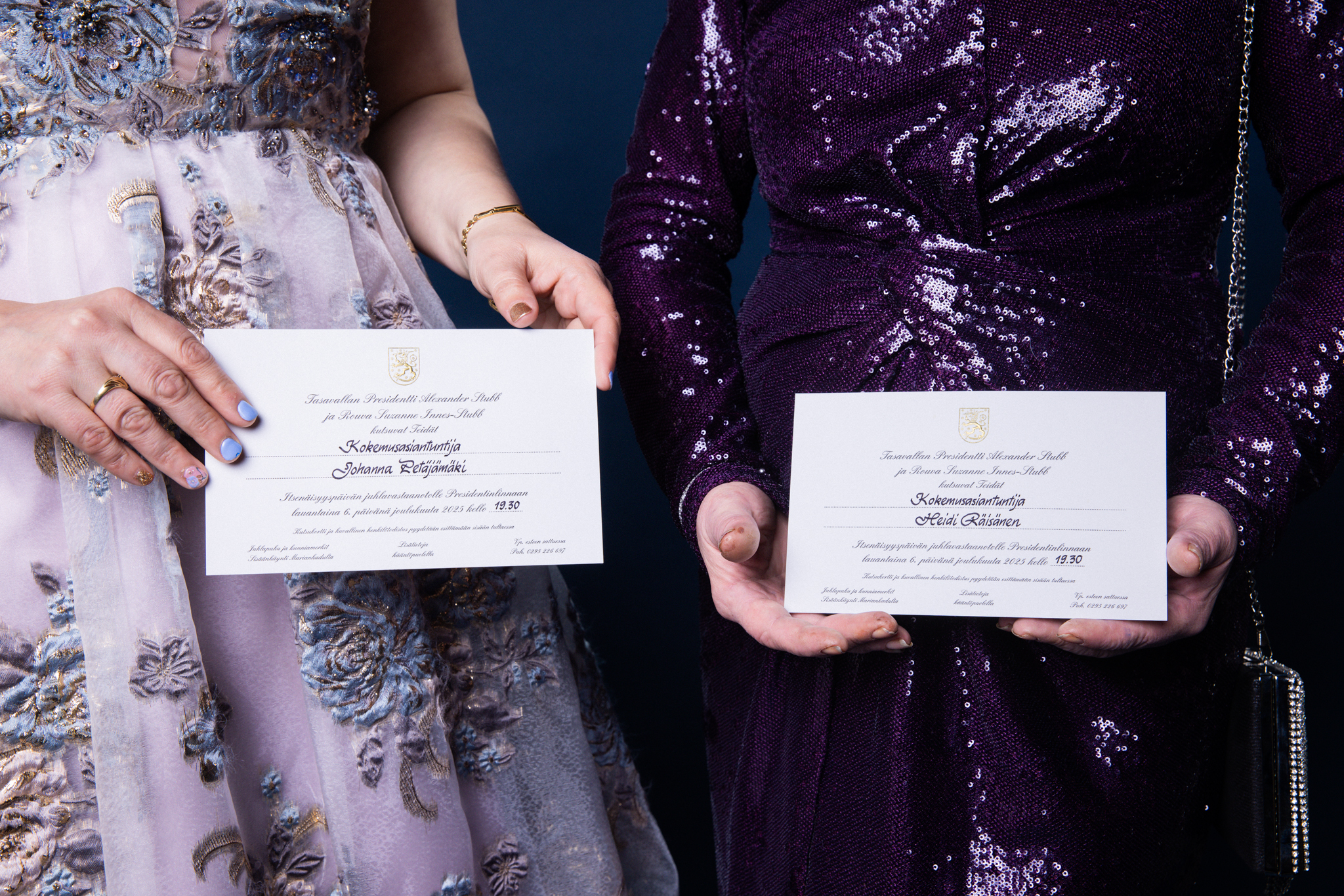 Kädet pitelevät Linnan juhlien kutsuja.