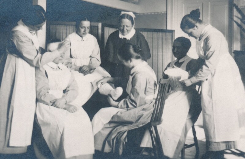 Mustavalkoinen historiallinen valokuva, jossa harjoitellaan raajojen sidontaa.