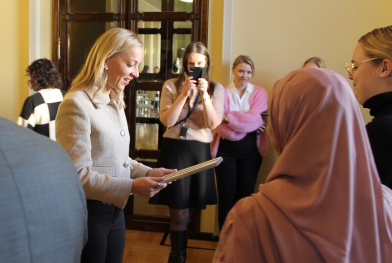 Nainen katsoo kädessään olevaa diplomia.