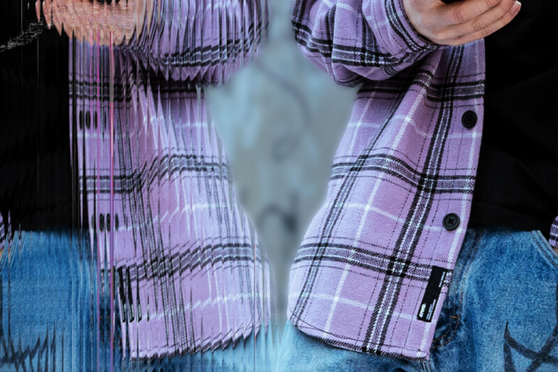 Violettiin flanellipaitaan pukeutunut henkilö pitää puhelinta kädessään.