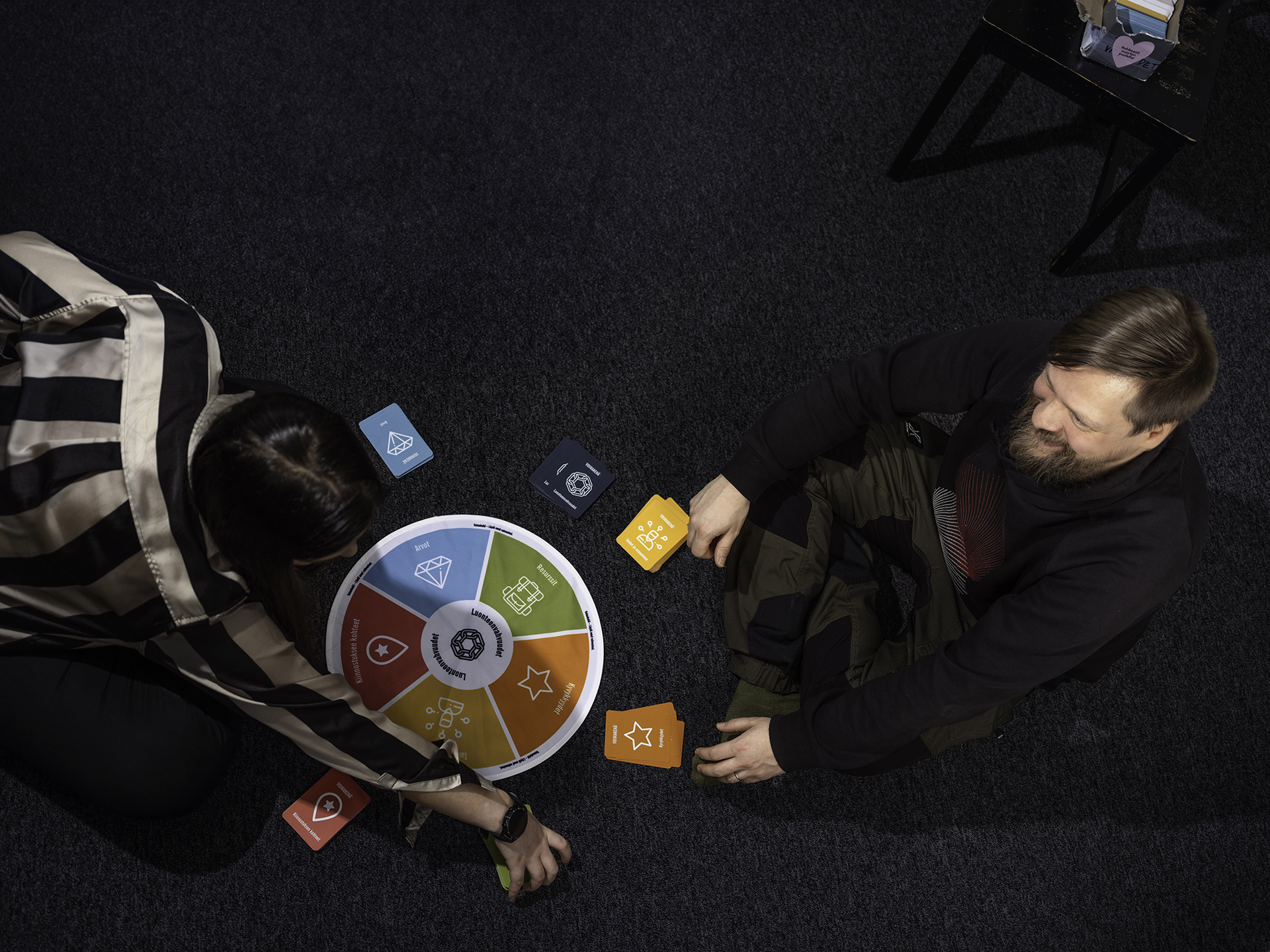 Nuori nainen ja mies istuvat lattialla ja pelaavat lautapeliä.