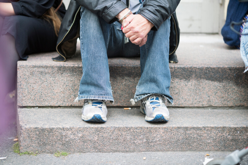 Tunnistamanton henkilö istuu betonirappusilla.