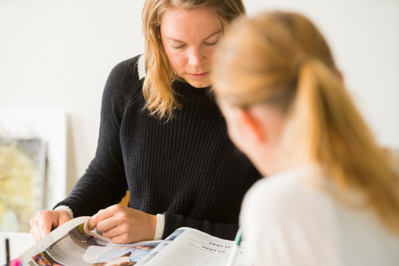 Kaksi henkilöä kumartuneena pöydän ylle.