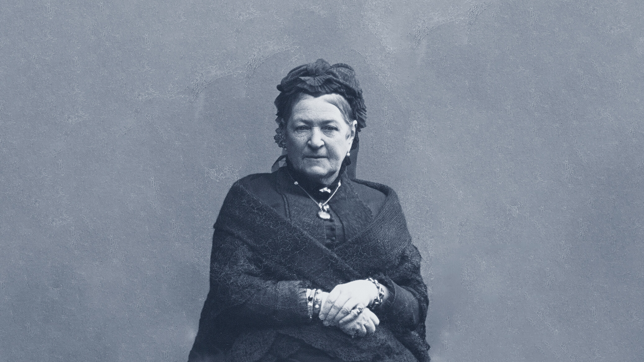 Mustavalkokuva iäkkäästä naisesta, joka katsoo vakavana kameraan.