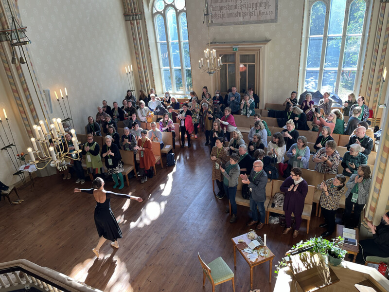 Diakonissalaitoksen kirkon sisätilassa suuri joukko ihmisiä katsoo tanssijaa, joka esiintyy kirkossa.