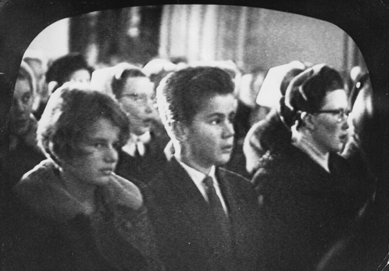 Ihmisiä istuu riveissä. he ovat kirkossa jumalanpalveluksessa. Vanha mustavalkoinen kuva.