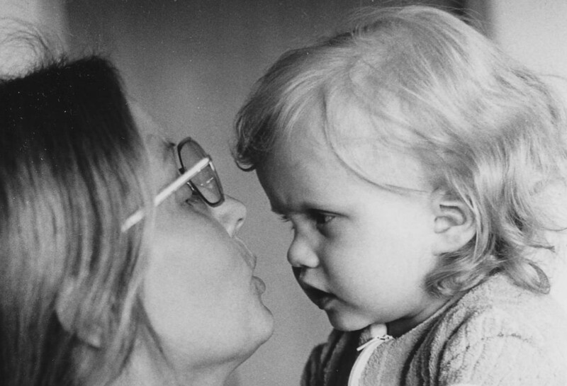 Musta-valkoinen kuva aikuisesta, joka katsoo hellästi pientä lasta kasvoihin.