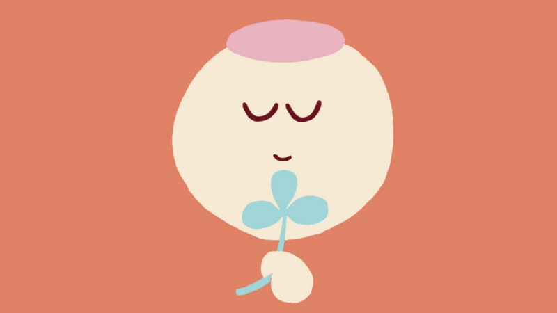 Yksinkertainen pastellipiirros: pyöreä kasvoinen hahmo silmät suljettuina ja lievä hymy, joka pitää käsissään pientä sinertävää kolmilehtistä kukkaa lämpimän terrakotanruskealla taustalla, kuva välittää rauhaa ja onnellisuutta.