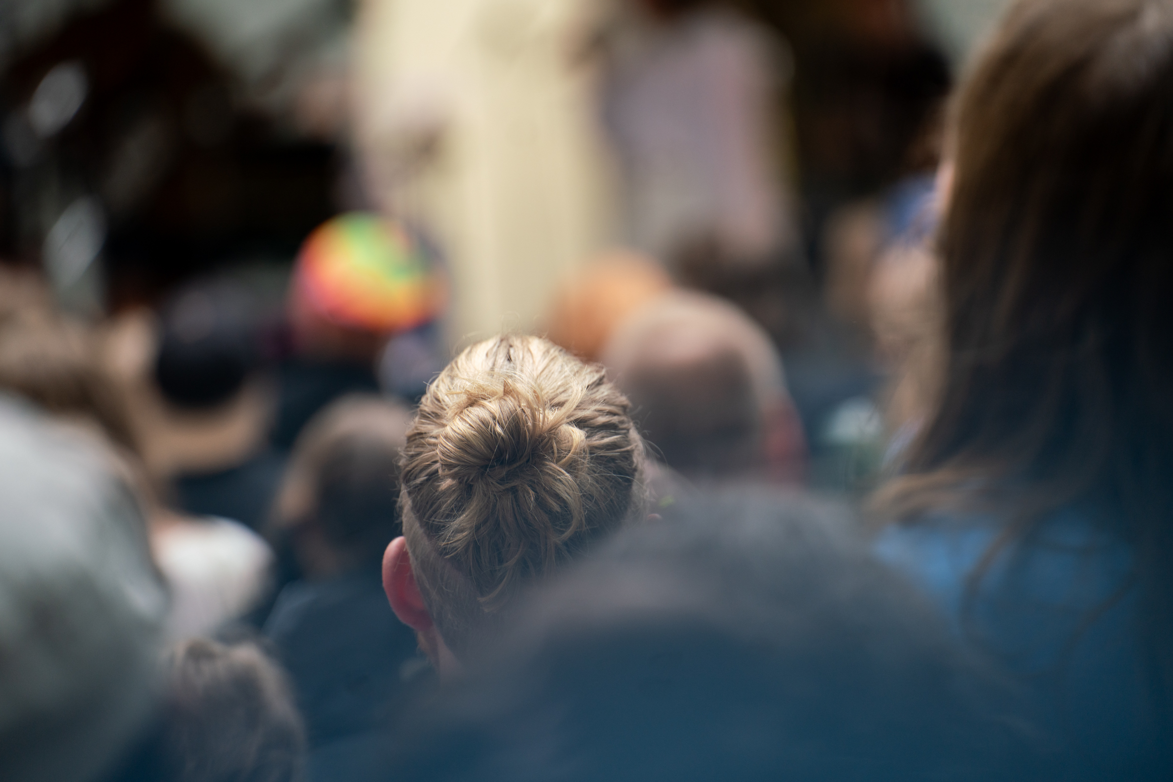 Konserttiyleisössä nutturahiuksinen nainen takaapäin kuvattuna ja tarkennettuna yleisön seasta