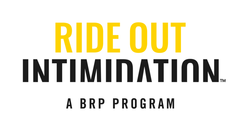 Logo, jossa iso keltainen teksti "RIDE OUT", sen alla tummanharmaa teksti "INTIMIDATION" ja vielä pienemmällä "A BRP PROGRAM".